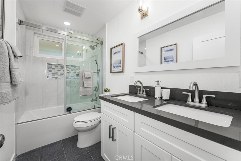 11344 Rochelle Street Los Alamitos, CA 90720 - Photo 31 of 55 a bathroom with a granite countertop sink a toilet a mirror a vanity a shower and vanity