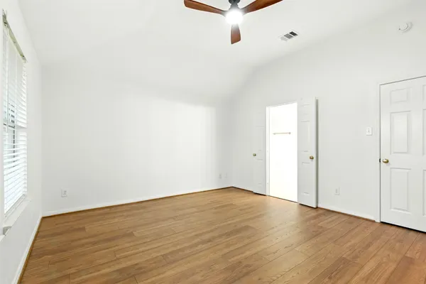 an empty room with wooden floor and windows
