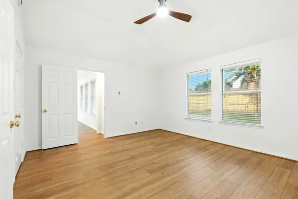 a view of an empty room with a window and wooden floor