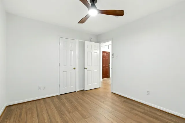 an empty room with wooden floor cabinet and ceiling fan