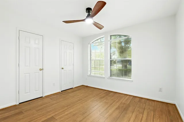 a view of an empty room with a window and wooden floor