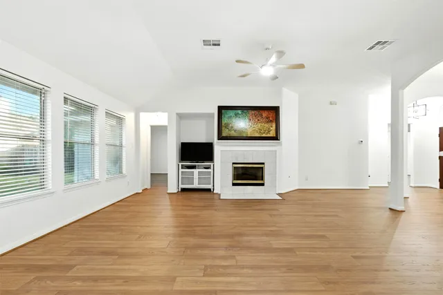 a view of a livingroom with a flat screen tv ceiling fan and fireplace