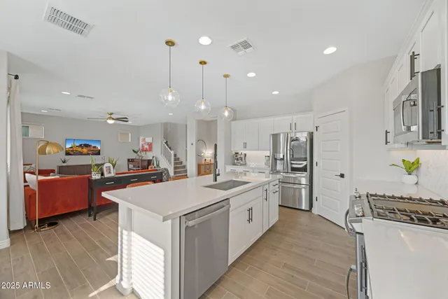 a kitchen with stainless steel appliances a sink dishwasher a refrigerator and cabinets with wooden floor