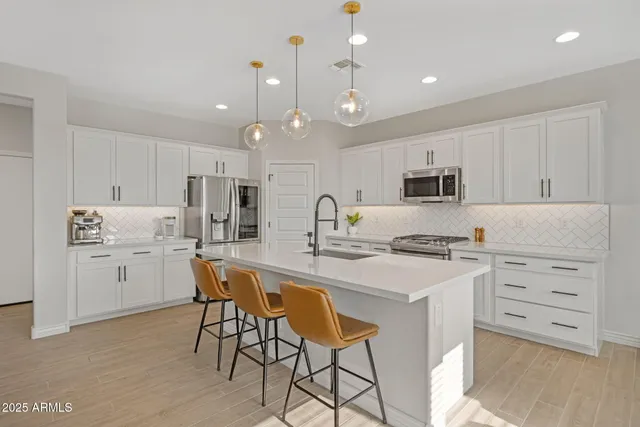 a kitchen with white cabinets and chairs