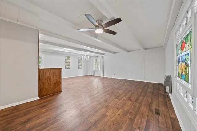 a view of a hallway with wooden floor and a kitchen