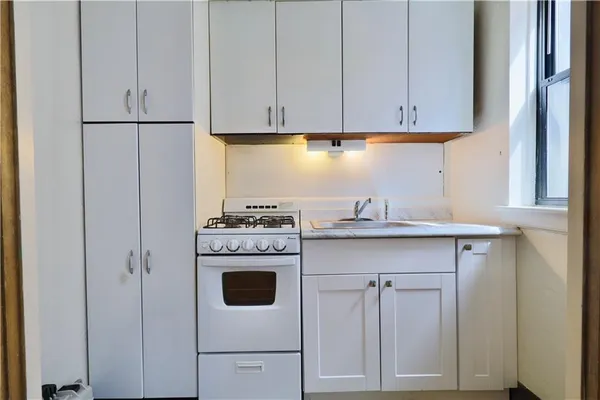 a kitchen with stainless steel appliances granite countertop a sink a stove a refrigerator and white cabinets