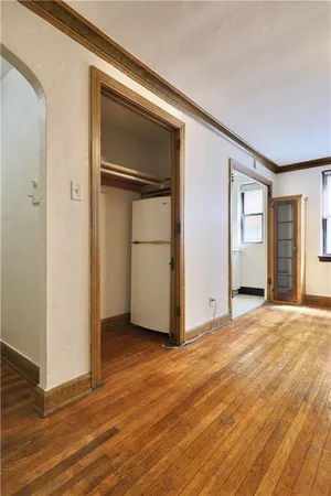 a view of an empty room with wooden floor and closet