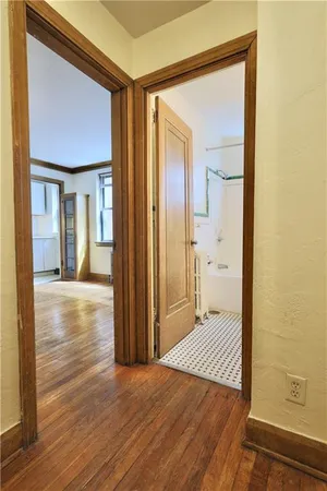 a view of a hallway with wooden floor and a bathroom