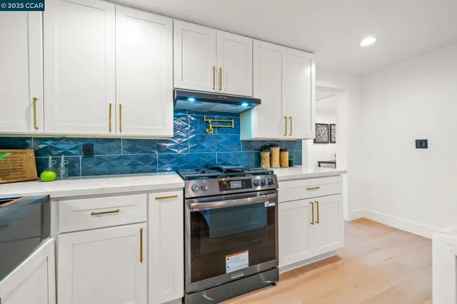 a kitchen with granite countertop white cabinets and stainless steel appliances