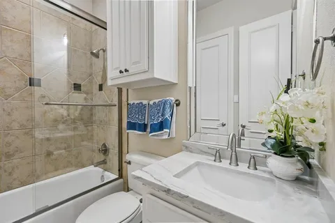 a bathroom with a granite countertop sink a toilet and shower