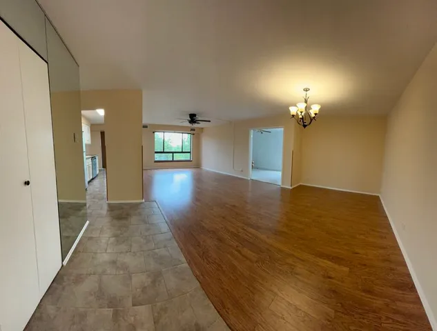 an empty room with wooden floor and chandelier
