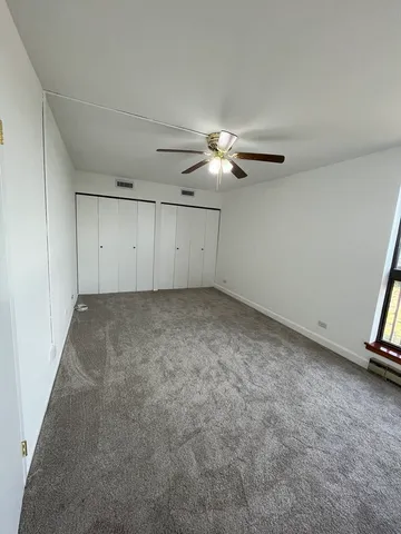 an empty room with a ceiling fan and a window