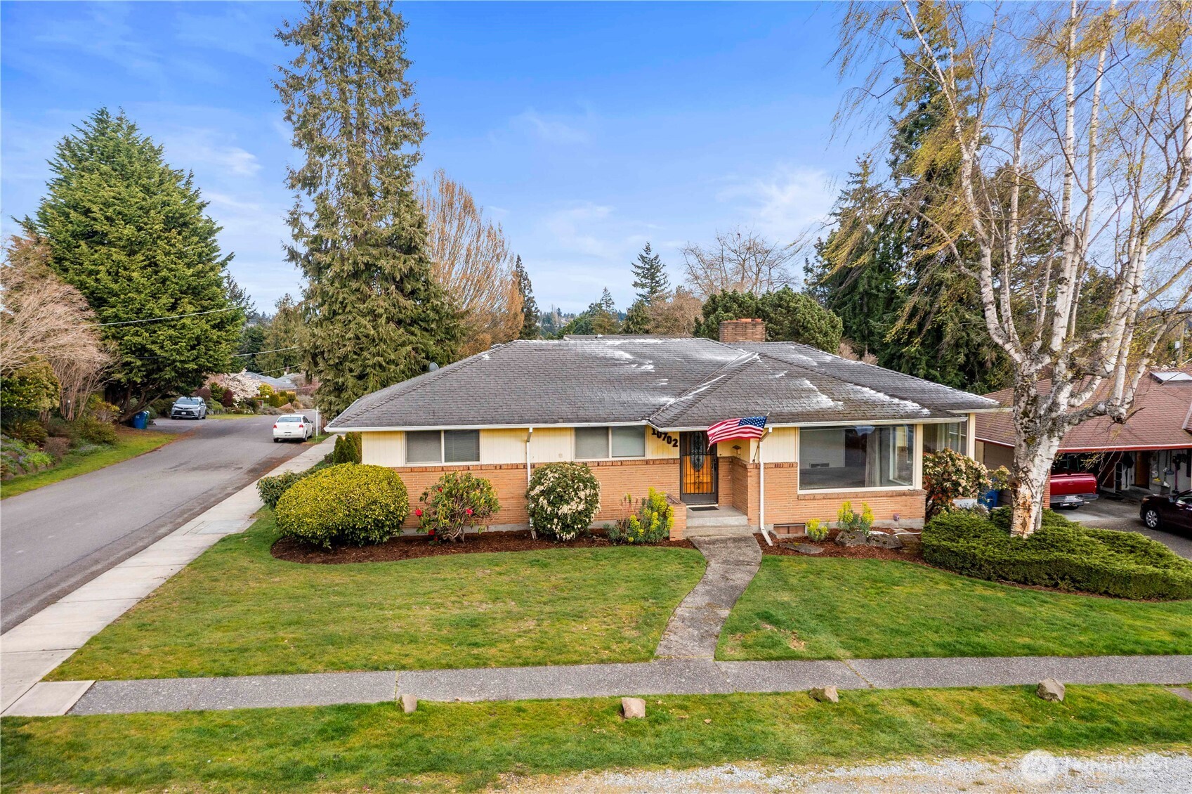 10702 39th Avenue Southwest Seattle, WA 98146 - Photo 35 of 40 a view of a white house with a yard plants and large tree