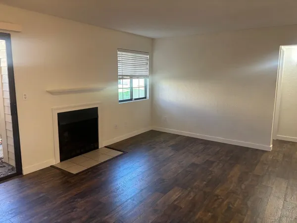 an empty room with wooden floor fireplace and windows