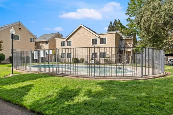a view of a white house and a park with a large tree
