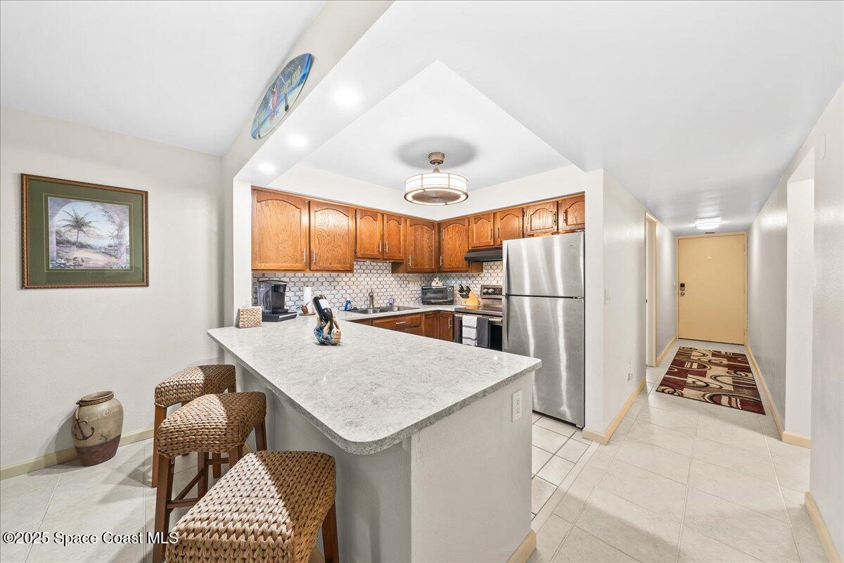 1700 South Atlantic Avenue, Unit 104 Cocoa Beach, FL 32931 - Photo 7 of 55 a kitchen with stainless steel appliances kitchen island granite countertop a refrigerator a oven a sink a dining table and chairs