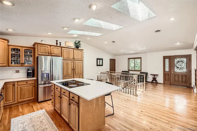 a kitchen with stainless steel appliances granite countertop a refrigerator oven stove a sink a dining table and chairs with wooden floor