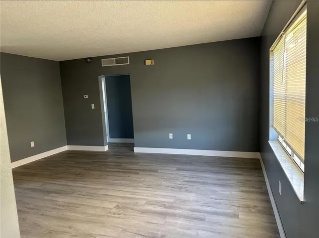 a view of an empty room with wooden floor and a window
