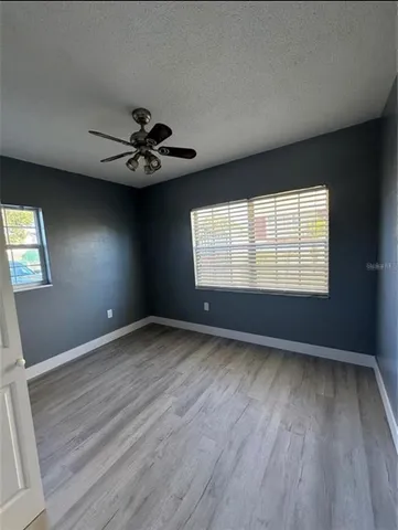 an empty room with windows and chandelier fan