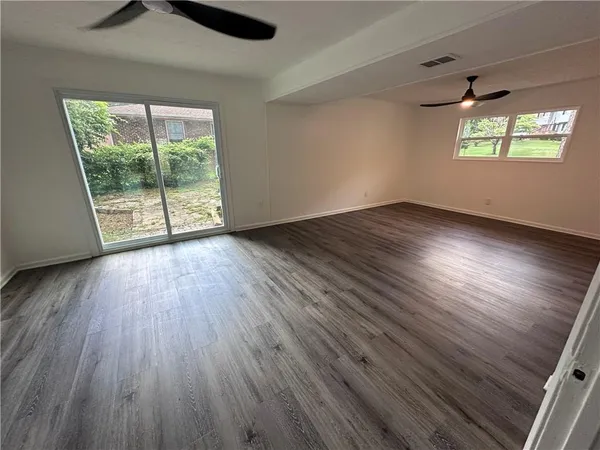 an empty room with wooden floor and windows
