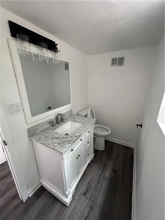 a bathroom with a granite countertop sink a toilet and a mirror