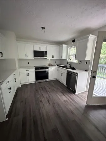 a large kitchen with cabinets wooden floor and stainless steel appliances