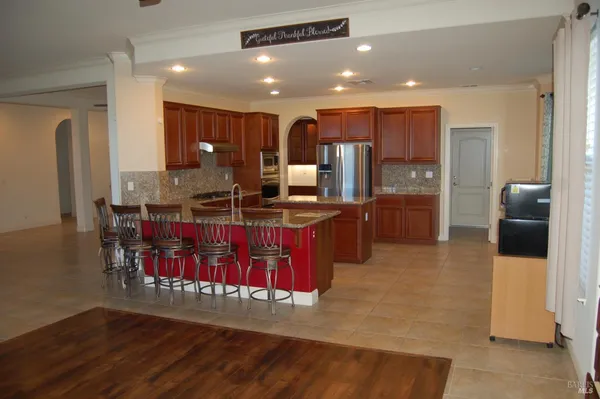a kitchen with stainless steel appliances kitchen island granite countertop a stove refrigerator and cabinets