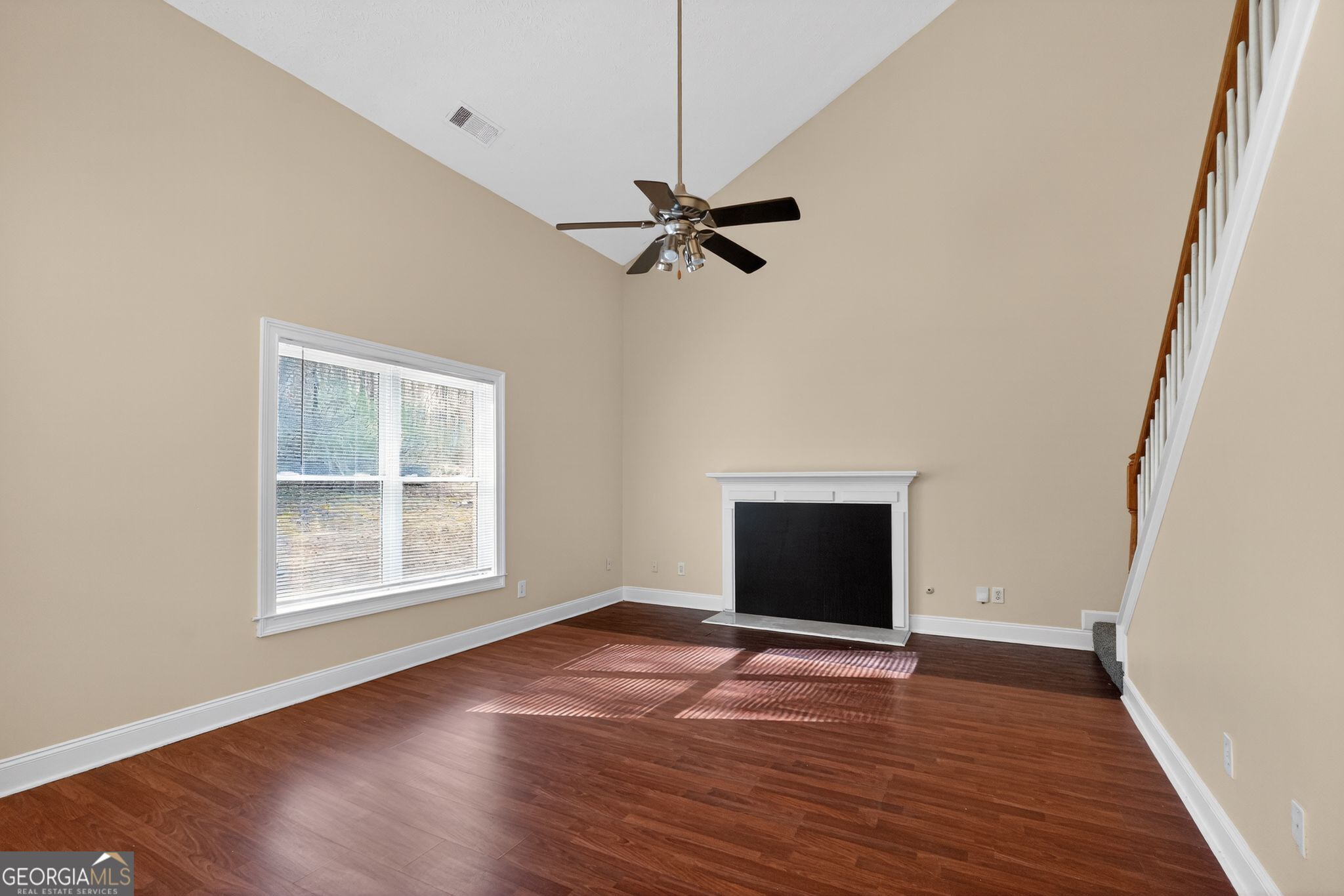 3960 East Saddle Ridge Drive Lithonia, GA 30038 - Photo 9 of 36 an empty room with wooden floor chandelier fan and windows