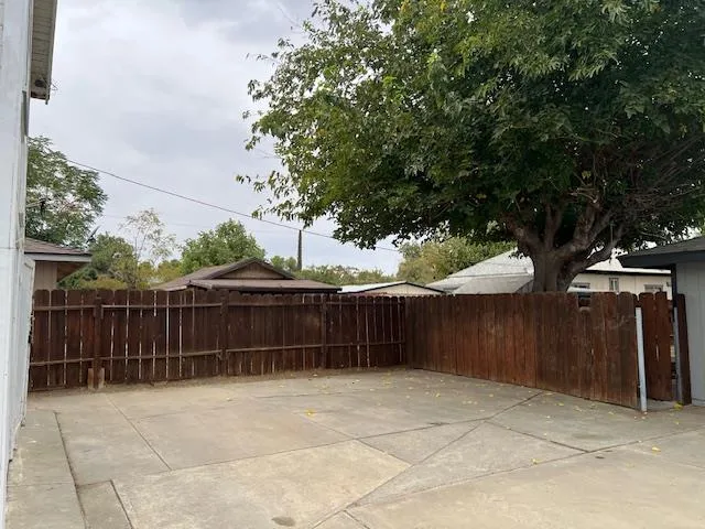 a view of backyard with green space and wooden fence