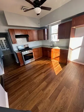 a living room with stainless steel appliances furniture a rug and a kitchen view