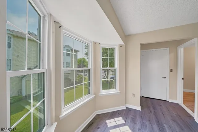 a view of an empty room with wooden floor and windows