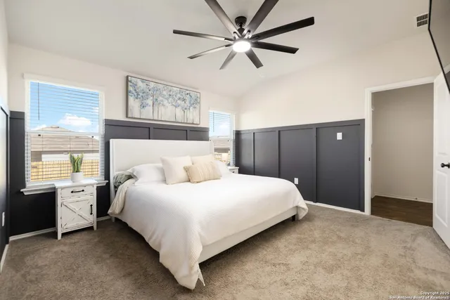 a bedroom with a large bed and a chandelier fan