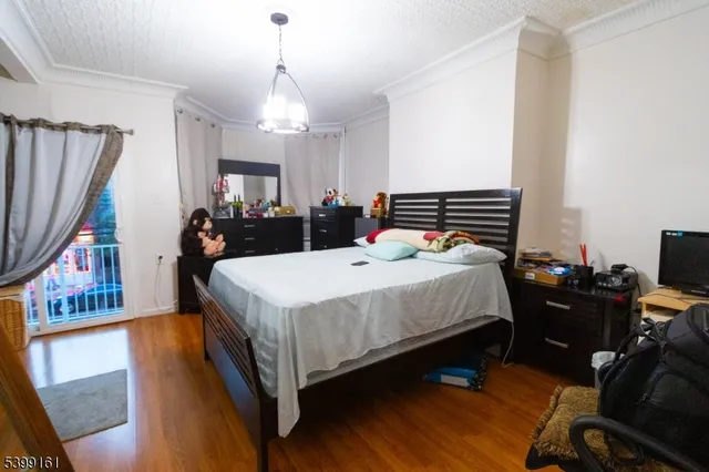 a bedroom with a bed a dresser and a chandelier