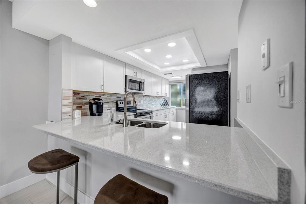 4620 Bay Boulevard, Unit 1117 Port Richey, FL 34668 - Photo 13 of 37 a kitchen with stainless steel appliances a sink a stove a refrigerator cabinets and chairs