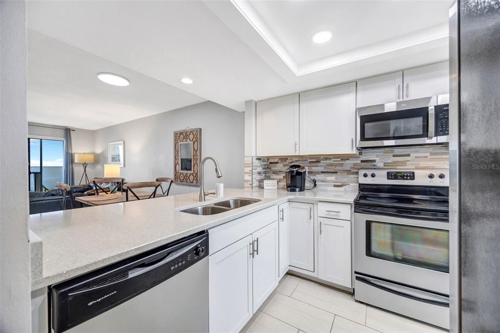 4620 Bay Boulevard, Unit 1117 Port Richey, FL 34668 - Photo 8 of 37 a kitchen with a stove white cabinets and stainless steel appliances