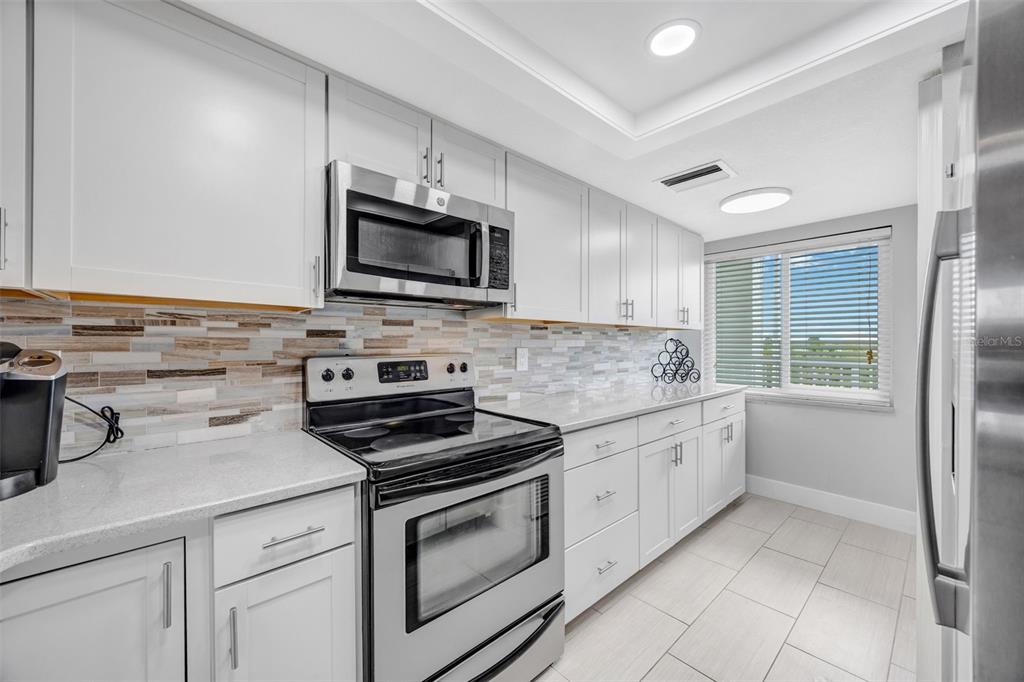 4620 Bay Boulevard, Unit 1117 Port Richey, FL 34668 - Photo 9 of 37 a kitchen with granite countertop white cabinets and stainless steel appliances