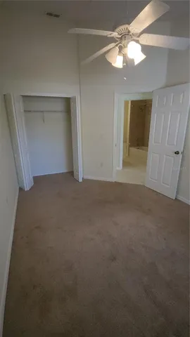 an empty room with a chandelier fan and windows