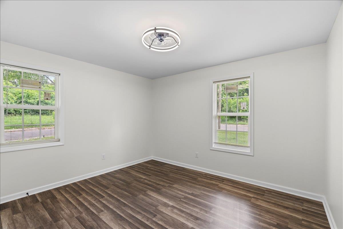 3065 Sax Road Memphis, TN 38109 - Photo 9 of 17 Spacious room featuring wood-finish flooring, two large windows, white walls, and a modern ceiling light fixture