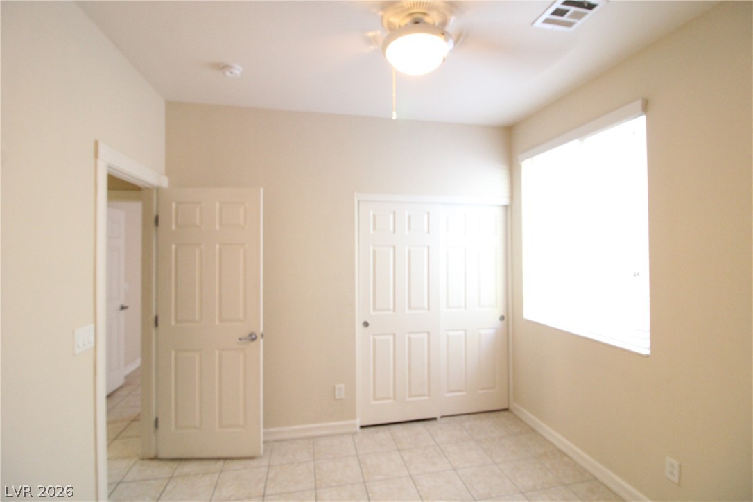 754 Rise Canyon Drive Henderson, NV 89052 - Photo 15 of 34 A well-lit bedroom features classic tile flooring and convenient sliding closet doors.