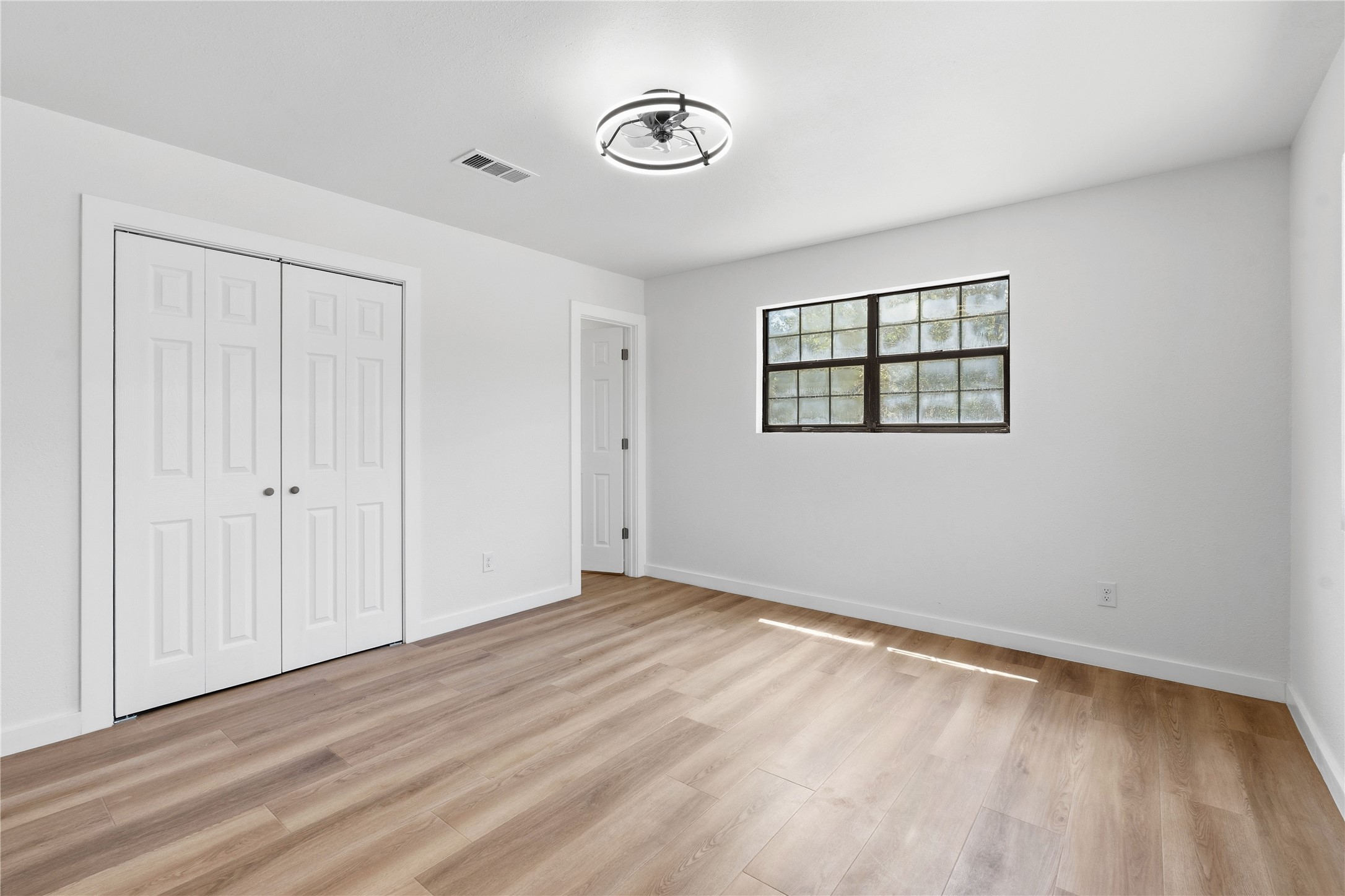 747 Chamberlin Road Dale, TX 78616 - Photo 10 of 28 A well-lit bedroom features durable laminate flooring and practical bi-fold closet doors.