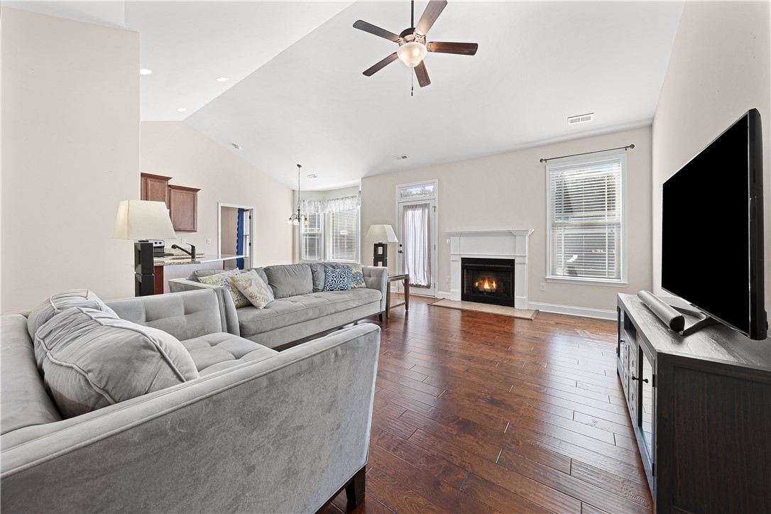 409 Coldstream Court Seneca, SC 29678 - Photo 12 of 40 This living area features a warm fireplace and rich hardwood flooring, perfect for cozy gatherings.