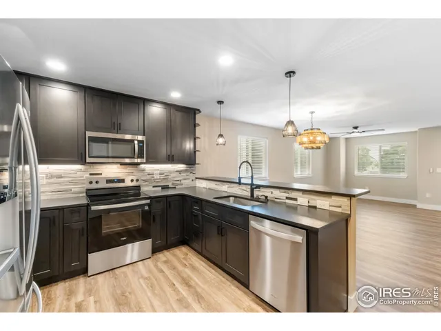 a kitchen with stainless steel appliances granite countertop a sink a stove and a refrigerator