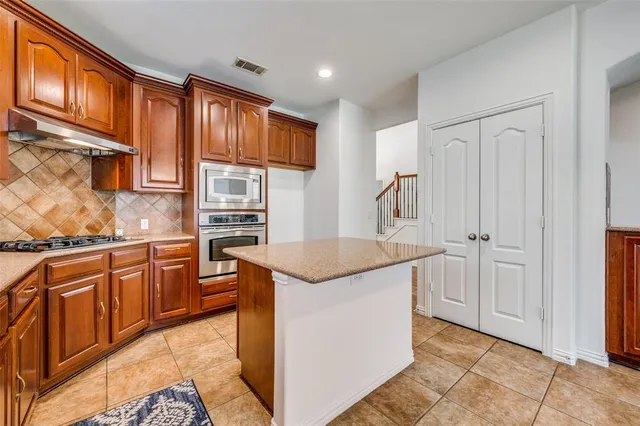 a large kitchen with granite countertop a large counter top stainless steel appliances and cabinets
