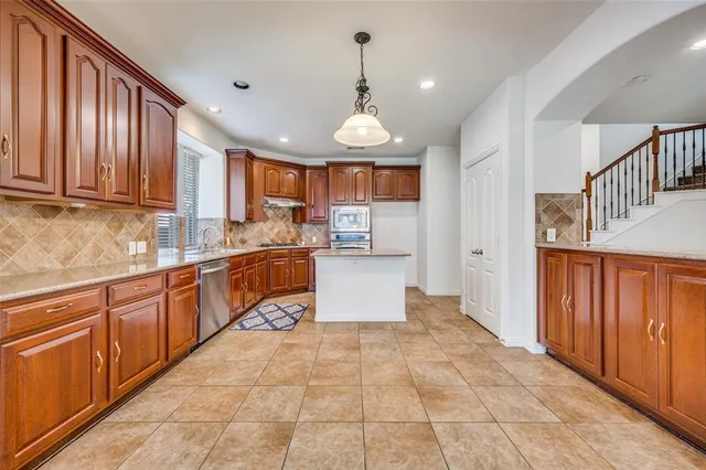 a kitchen with stainless steel appliances granite countertop a stove a sink and a refrigerator