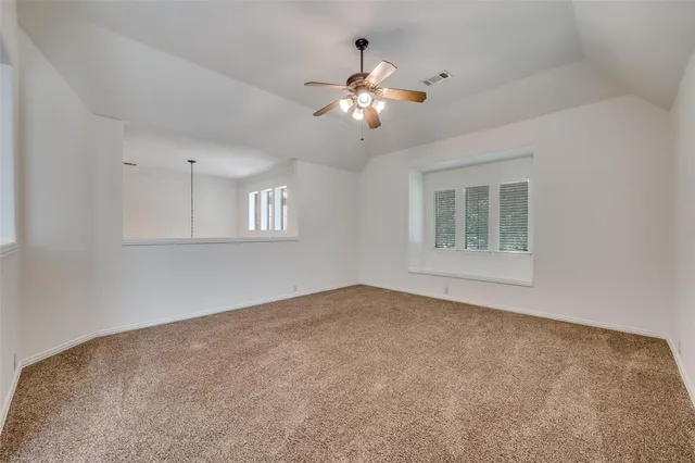 a view of an empty room with chandelier fan