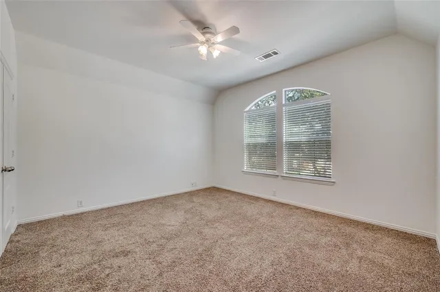 an empty room with a chandelier fan and windows