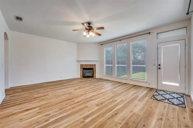 a view of an empty room with a window and wooden floor