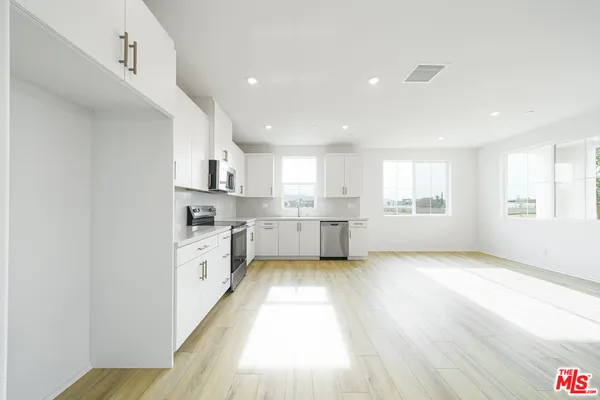 a large kitchen with a wooden floor and window