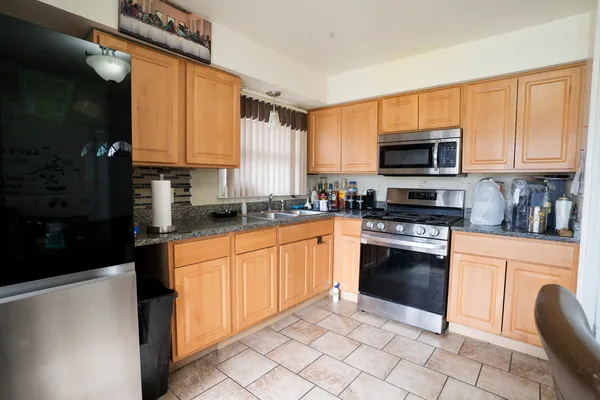 a kitchen with stainless steel appliances granite countertop a stove top oven a sink dishwasher a refrigerator and a microwave oven