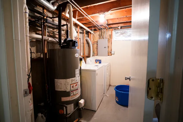 a view of storage and utility room with water heater and racks on the wall